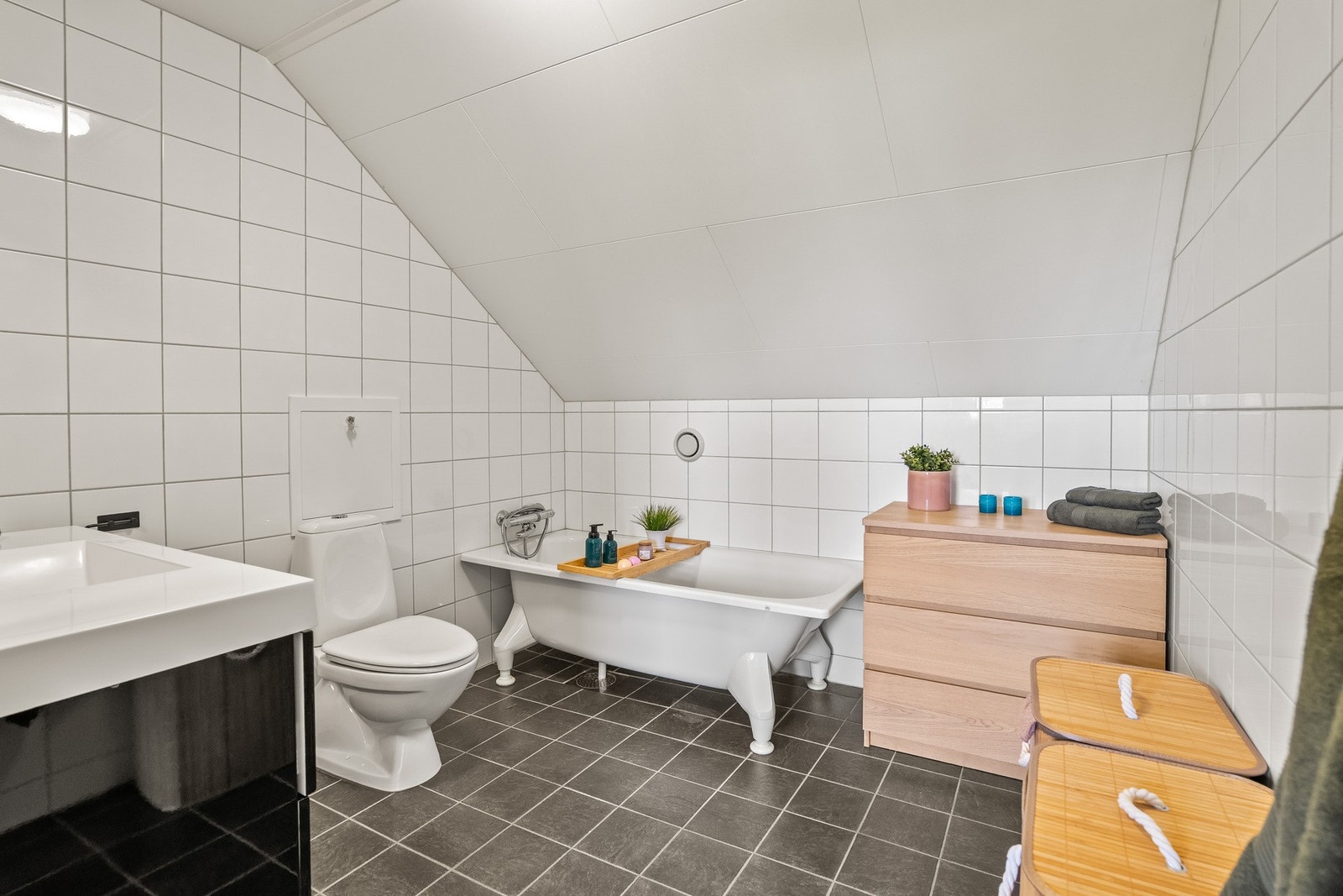Badet er innredet med heldekkende servant, speil med belysning, toalett og badekar med dusjbatteri. Rommet har også plass til ytterligere baderomsmøblement. Galleribilde