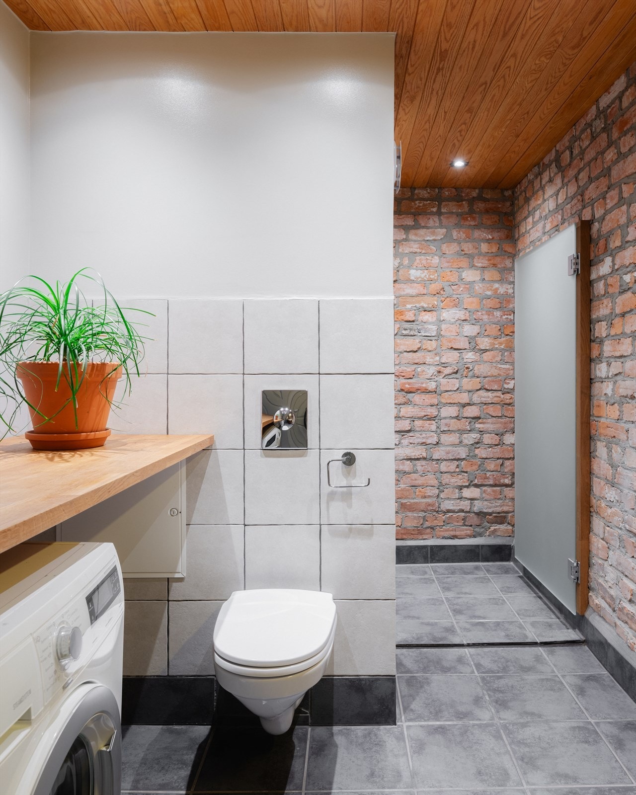 Badet har flislagt gulv med termostatstyrte varmekabler og en kombinasjon av fliser, malte overflater og teglstein på veggene. Galleribilde
