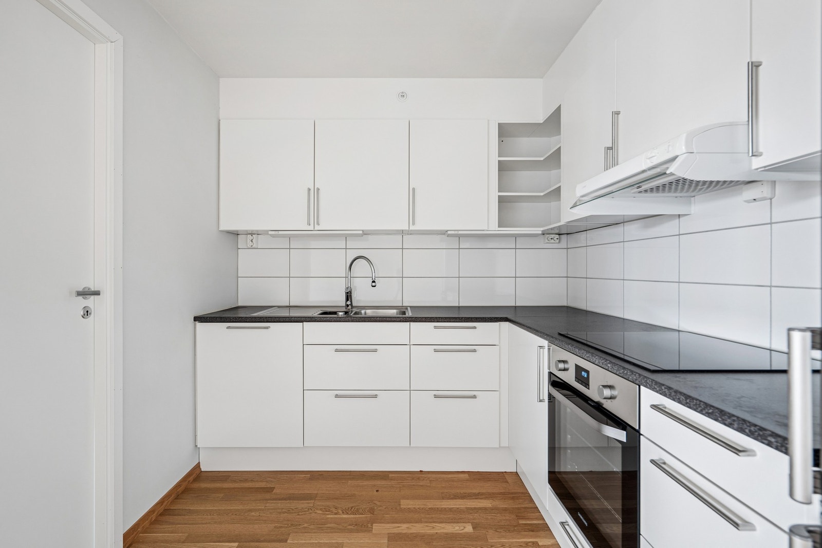 Kjøkkeninnredning med glatte fronter, laminatbenkeplate og fliser over arbeidsbenken. Galleribilde