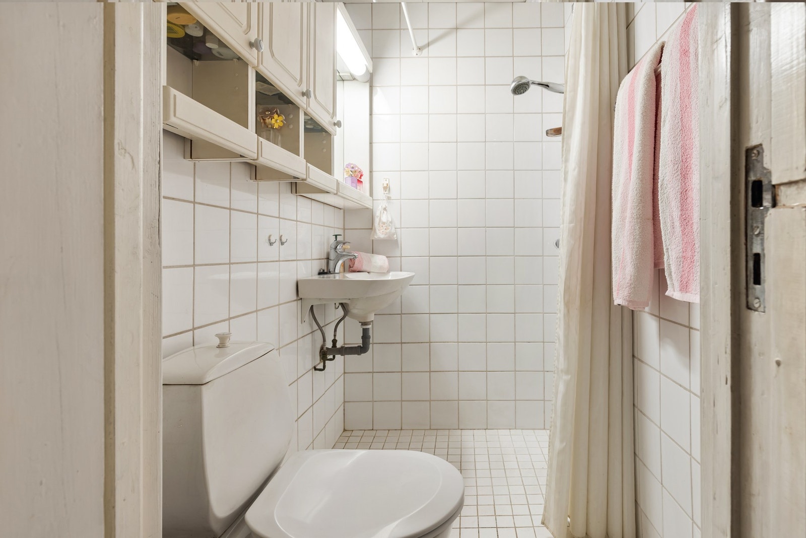 Badet fra 1980 har flislagte overflater og er innredet med servant, gulvmontert toalett og dusjløsning med forheng. Galleribilde
