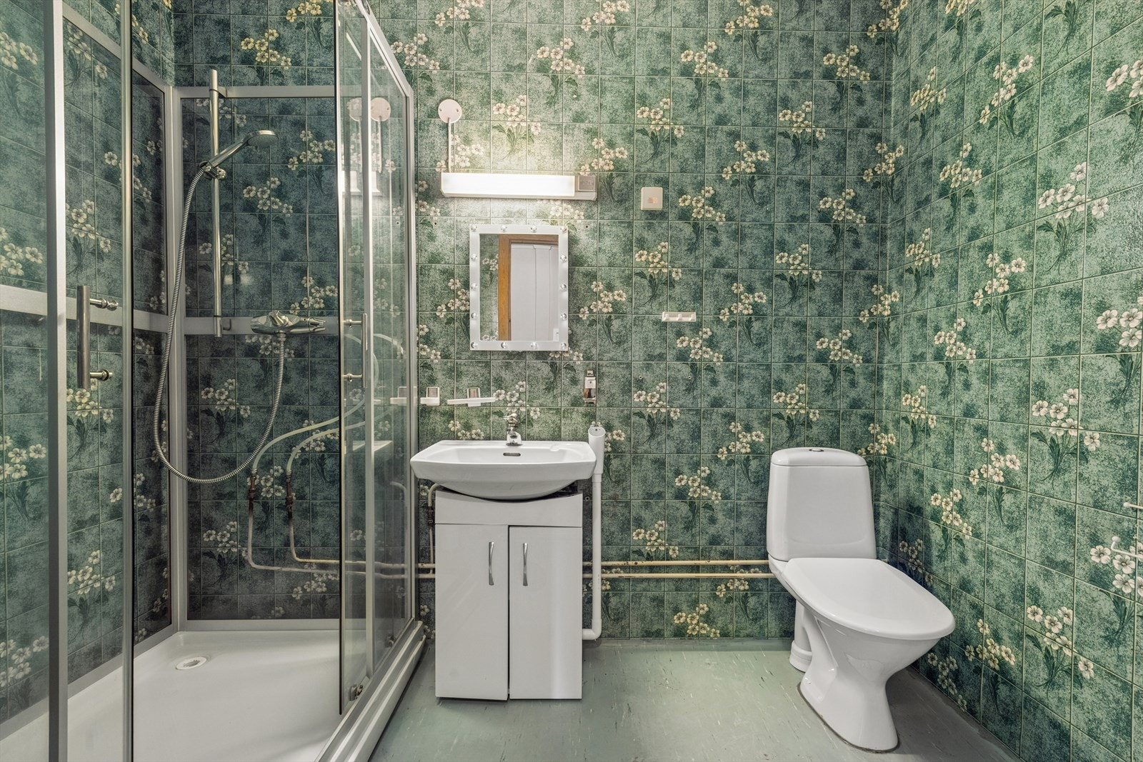 Badet har eldre standard med vinylbelegg på gulv og våtromstapet. Galleribilde