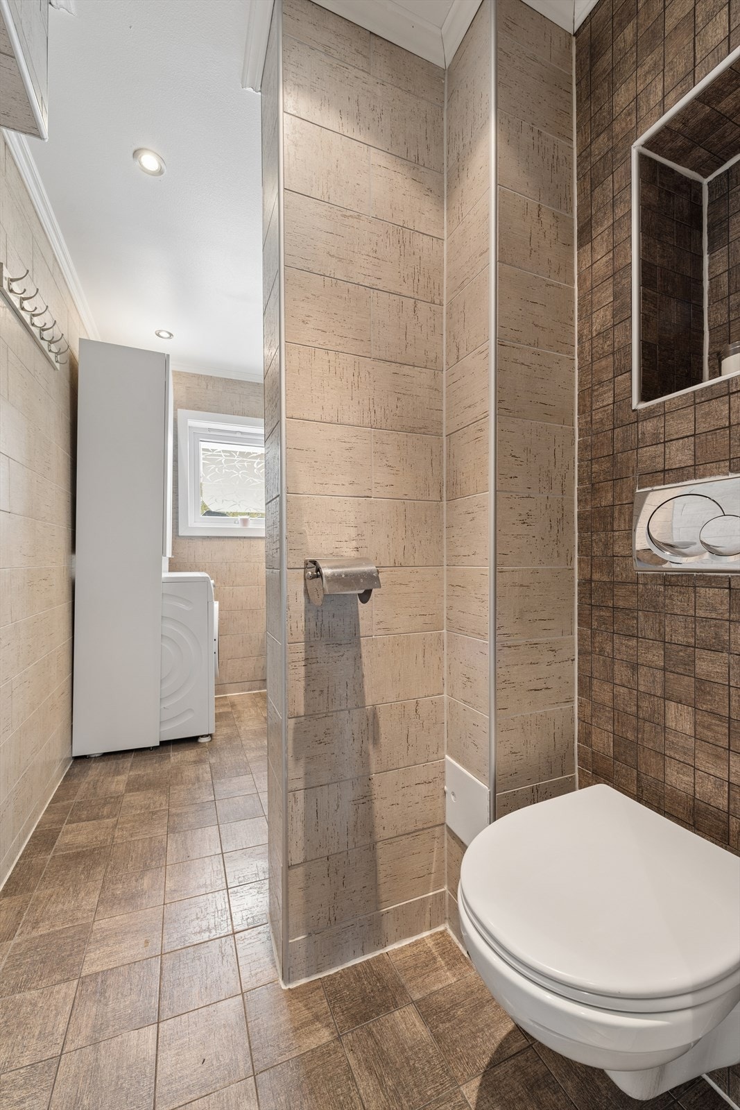 Badet er utstyrt med nedfelt servant, toalett og speilskap med belysning. Det er elektriske varmekabler i gulv og vaskemaskin som medfølger salget. Galleribilde
