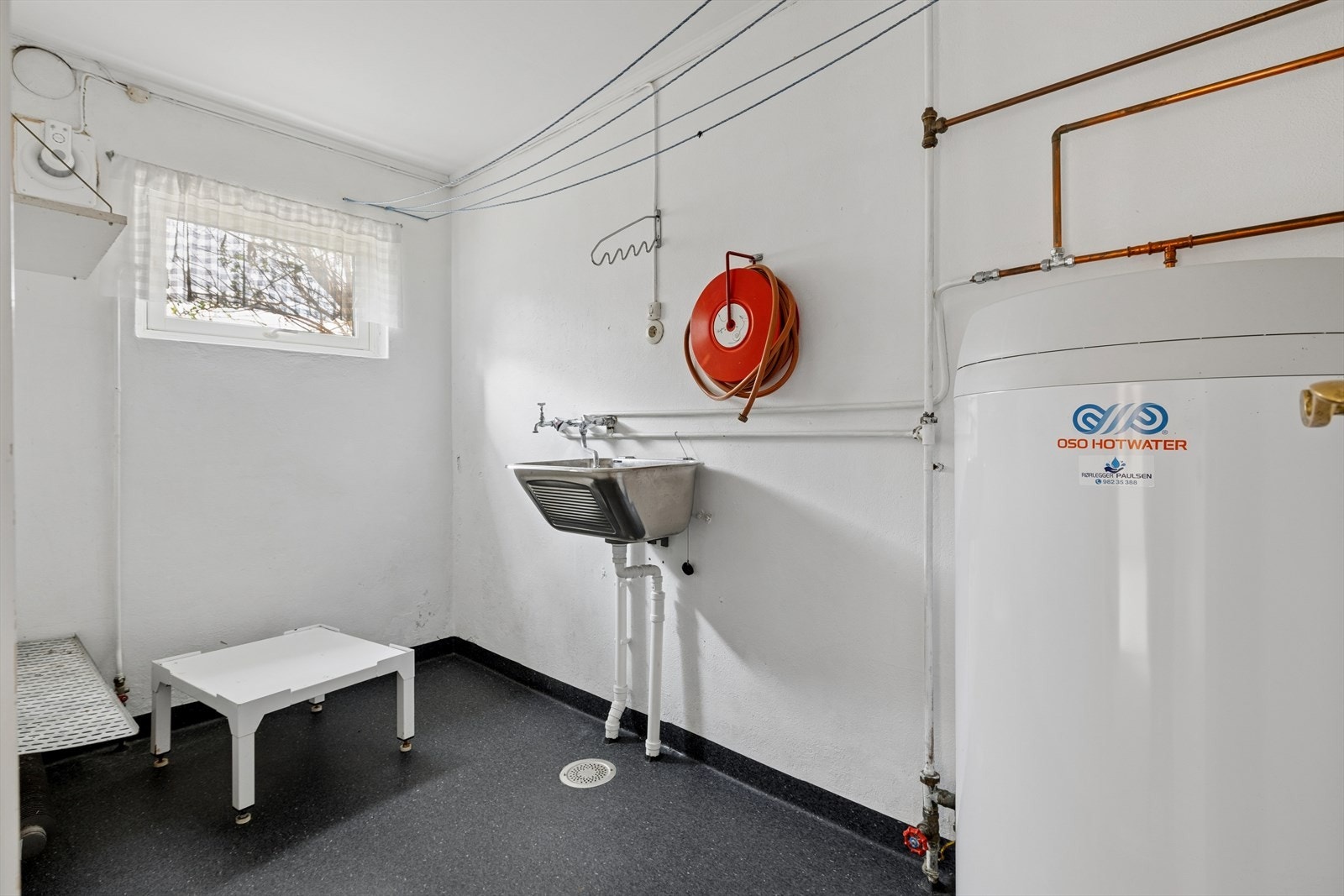 Praktisk vaskerom i underetasjen med utslagsvask i stål og opplegg for vaskemaskin. Galleribilde