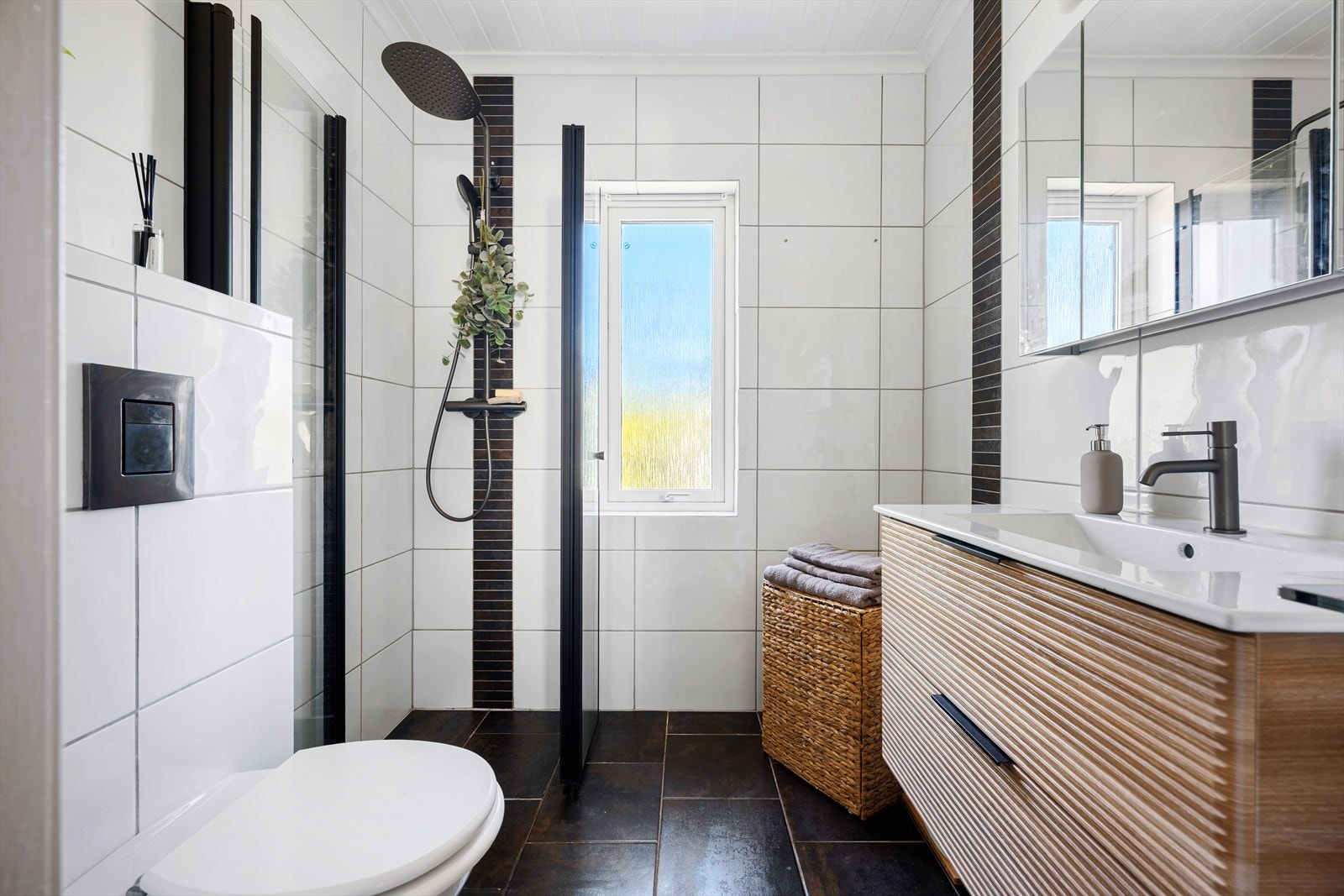 Badet i hovedetasjen har flislagt gulv med varmekabler og en moderne baderomsinnredning med god oppbevaringsplass. Galleribilde