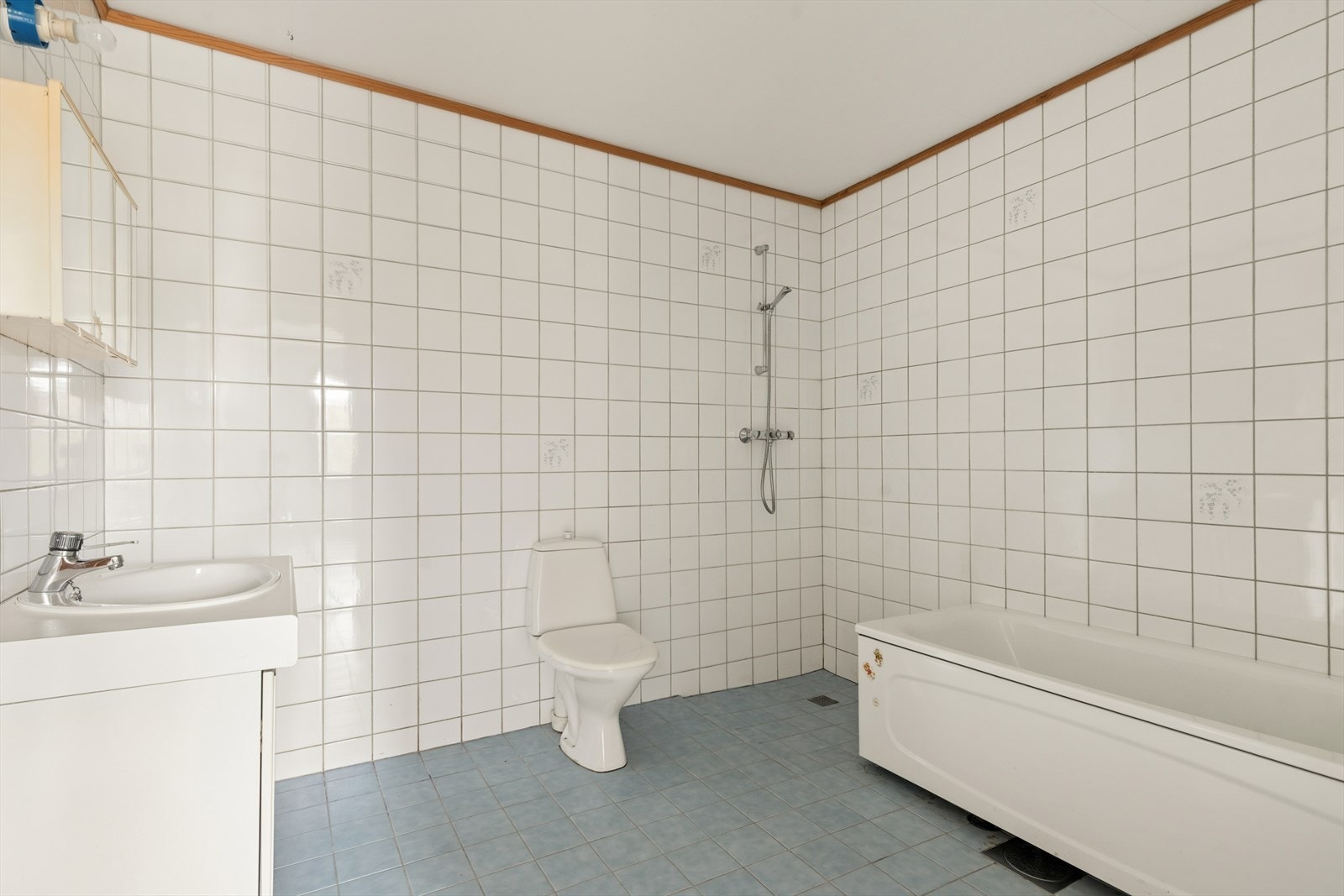 Baderommet i sokkeletasjen har fliser på gulv og vegger, badekar, dusj og opplegg for vaskemaskin. Galleribilde