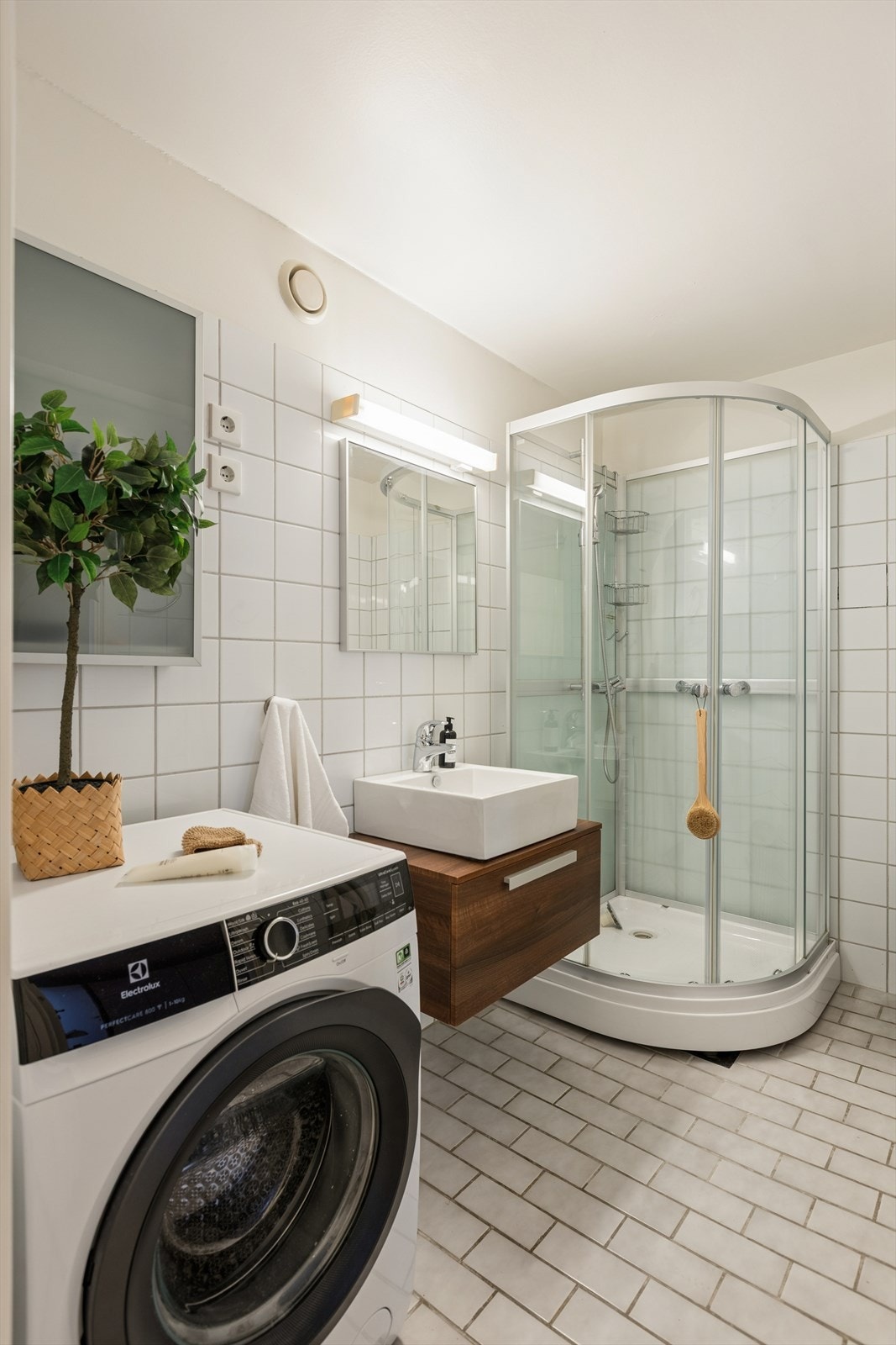 Badet har flislagt gulv med elektriske varmekabler, dusjkabinett og opplegg for vaskemaskin. Galleribilde
