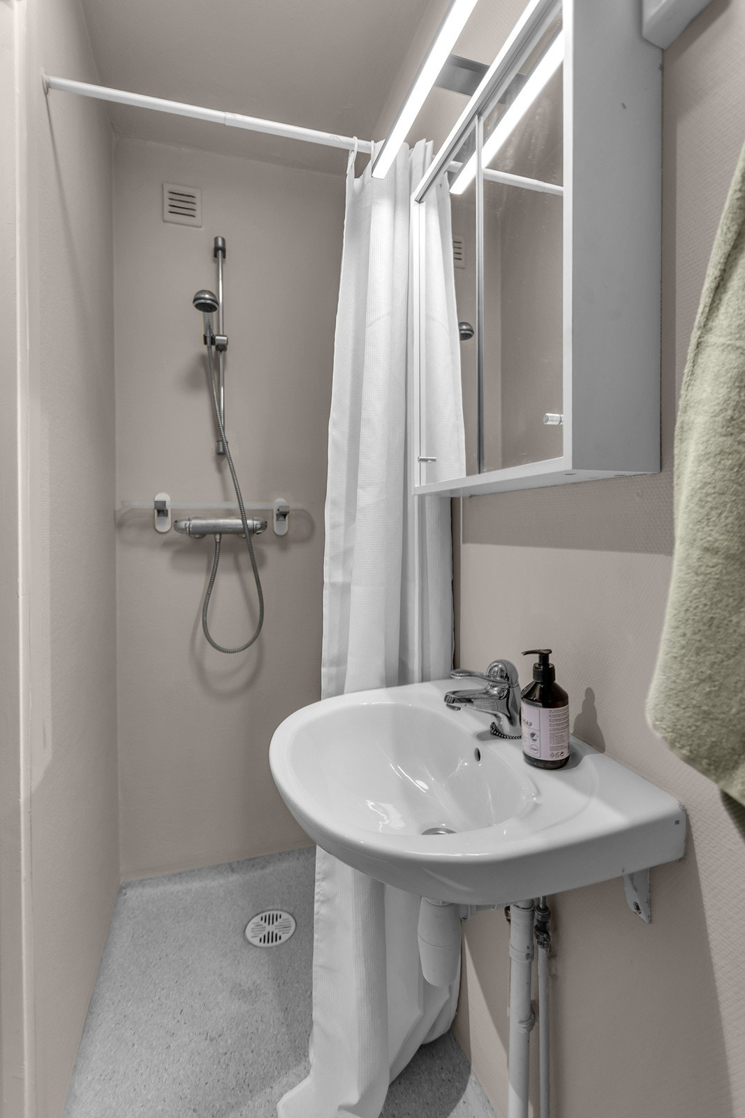 Badet har enkel standard med baderomsbelegg på gulv og tapet på vegger Galleribilde