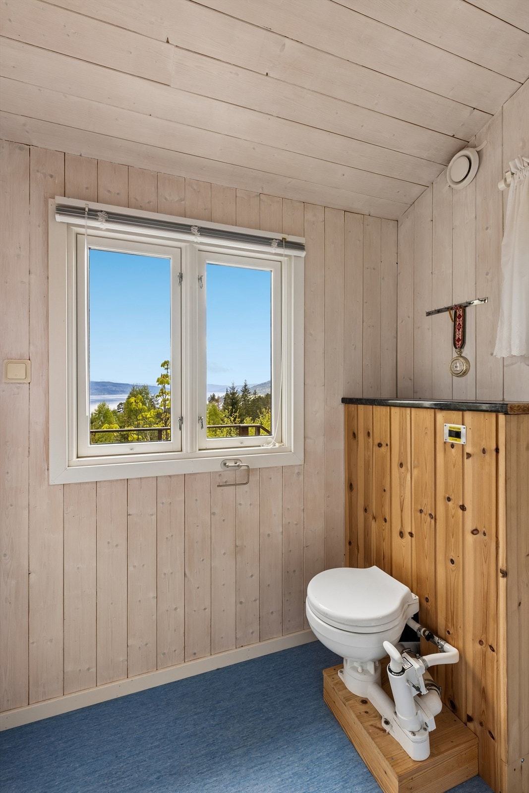 Enkelt hyttebad med pumpetoalett og utsikt mot naturen og fjorden Galleribilde