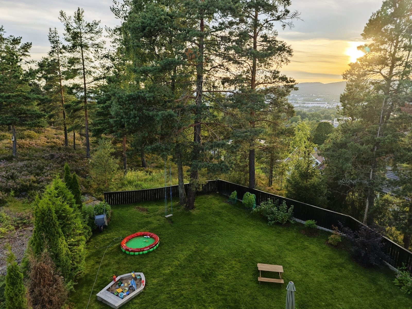 Selgers private bilde av hage med nydelig solnedgang. Hagen har gode solforhold og plass til både sitteområder, lek og beplantning, noe som gjør utearealet funksjonelt og fleksibelt gjennom ulike årstider. Galleribilde