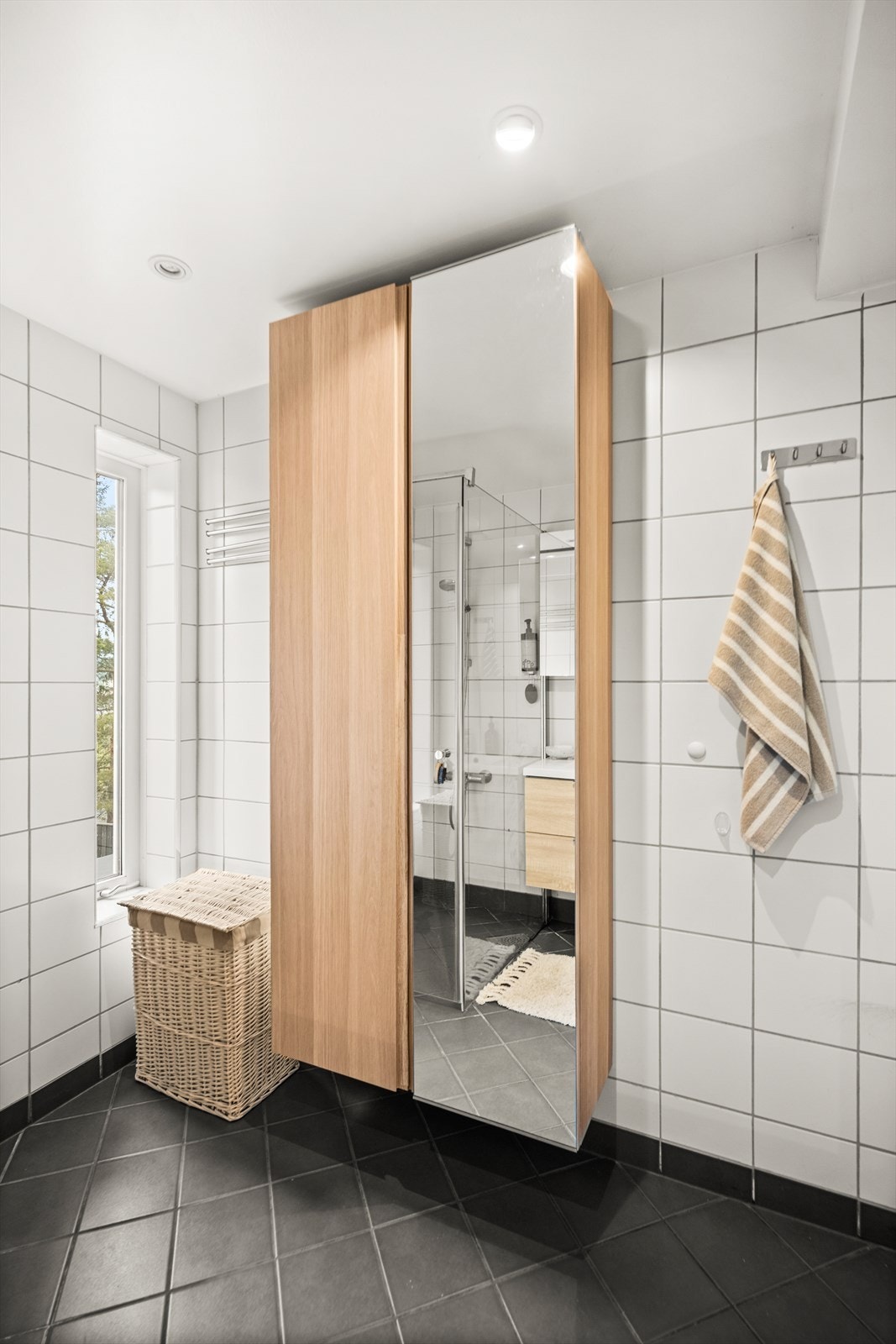 Badet er innredet med nedfelt servant med underskap, speilskap, vegghengt toalett og dusjhjørne med glassdører. Galleribilde