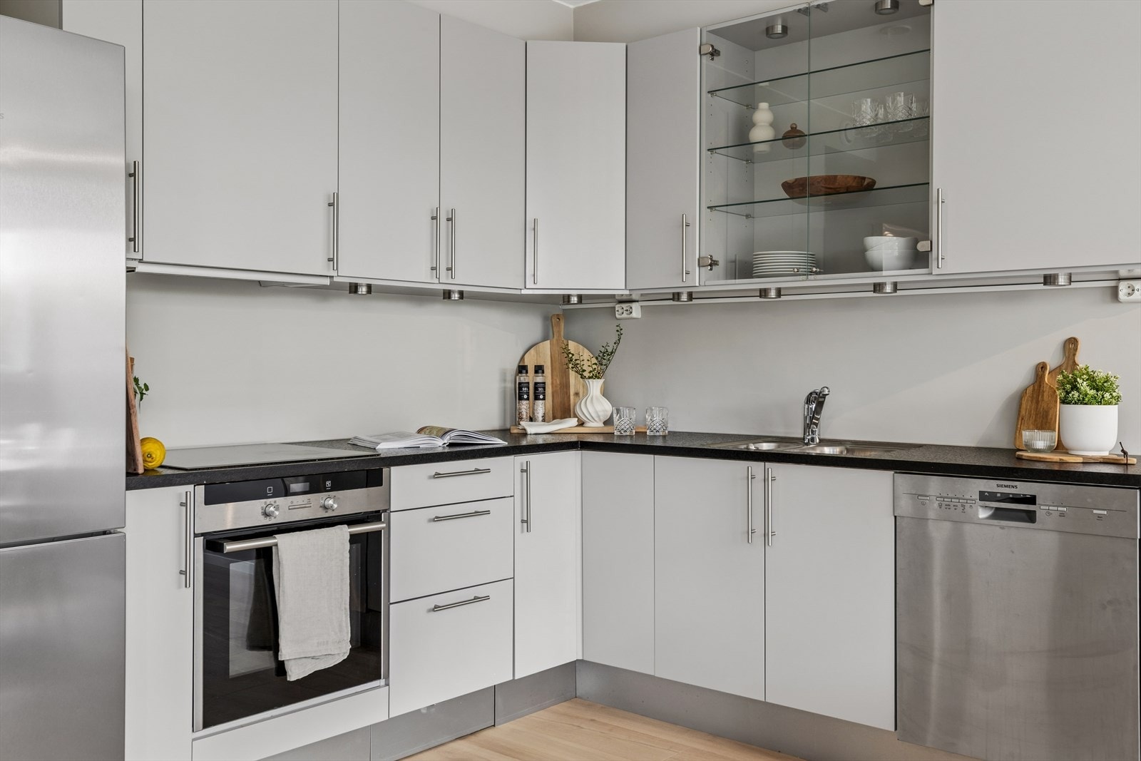 Kjøkkenet fremstår som moderne og funksjonelt med stilrene, glatte fronter og laminert benkeplate med nedfelt oppvaskkum i stål. Galleribilde