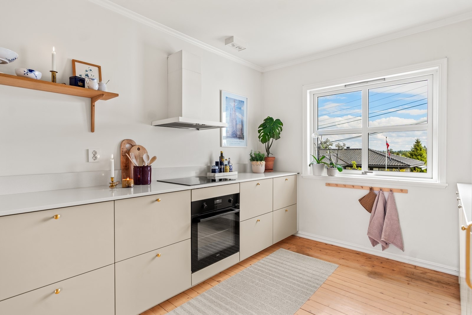 Beige kjøkkeninnredning med glatte fronter og benkeplate i kompositt. Galleribilde