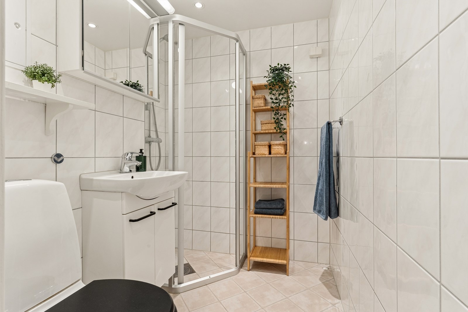 Flislagt baderom bestående av wc, servant m/underskap, speil, veggskap og dusj med skyvedører Galleribilde