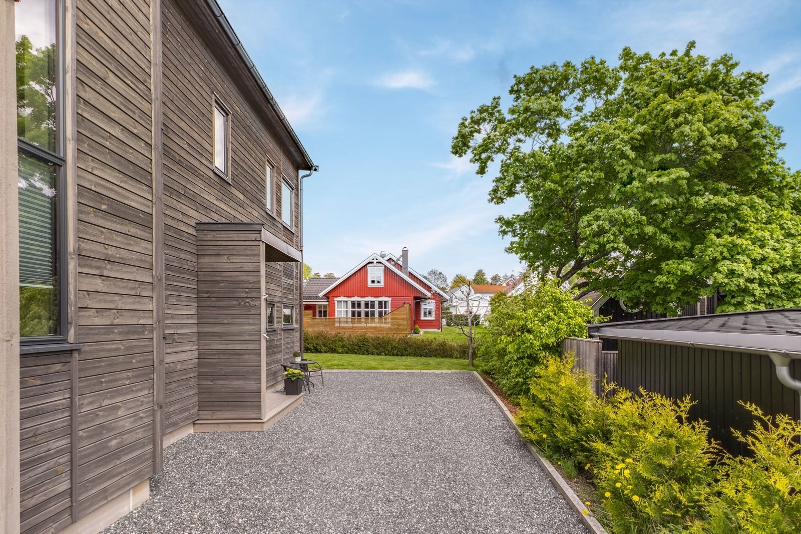 Gruset gårdsplass med parkeringsmuligheter foran inngangspartiet. Galleribilde