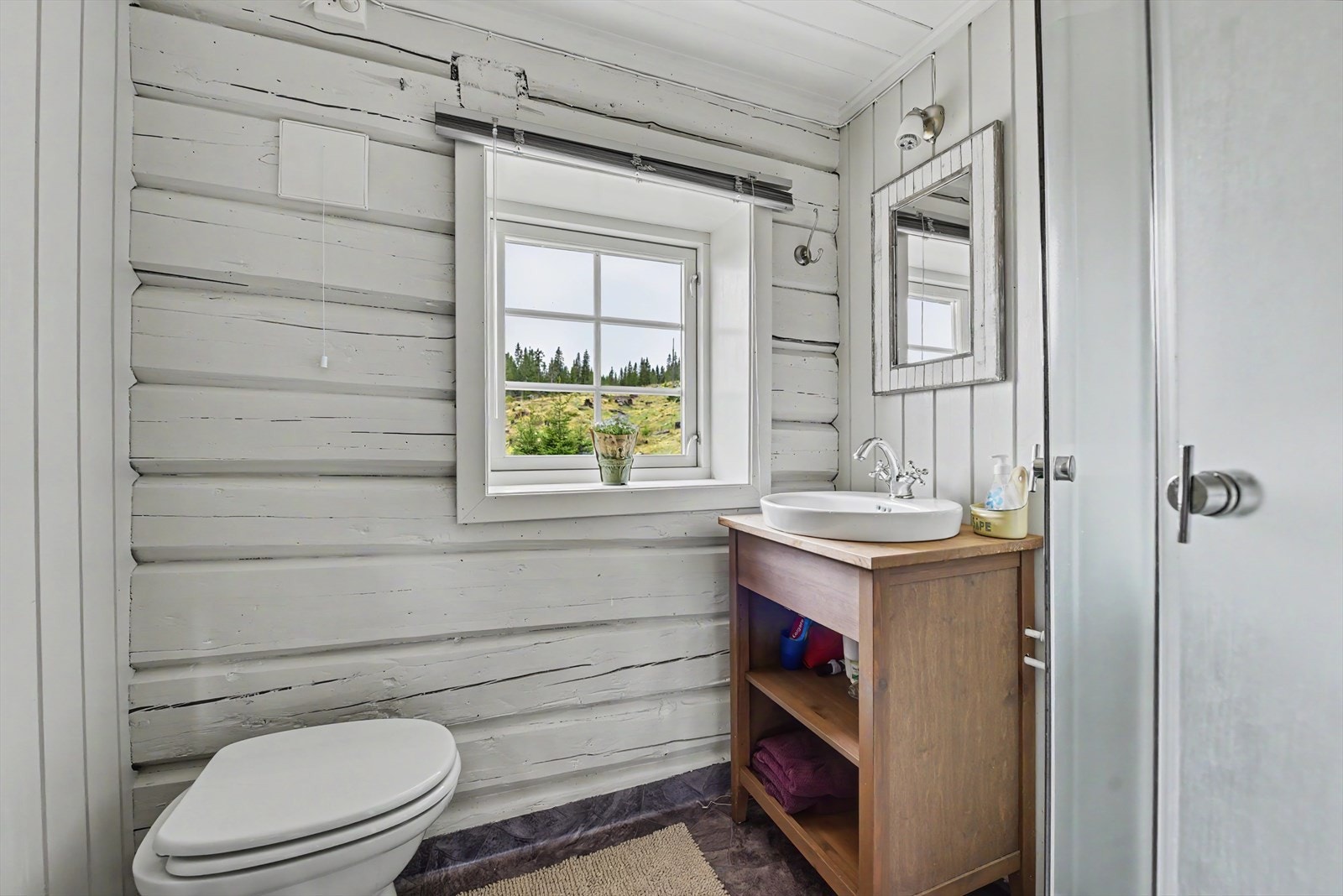 Badet er utstyrt med servant i skap, speil med belysning og dusjkabinett. Galleribilde