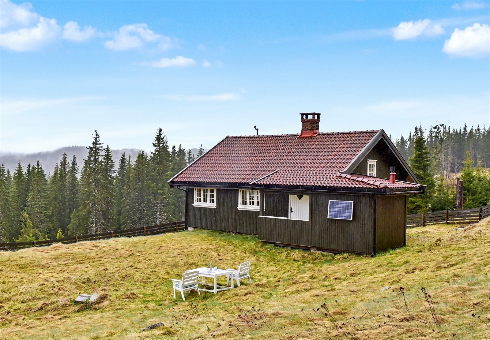 Hytta ligger på en festet naturtomt, omkranset av skog. Galleribilde