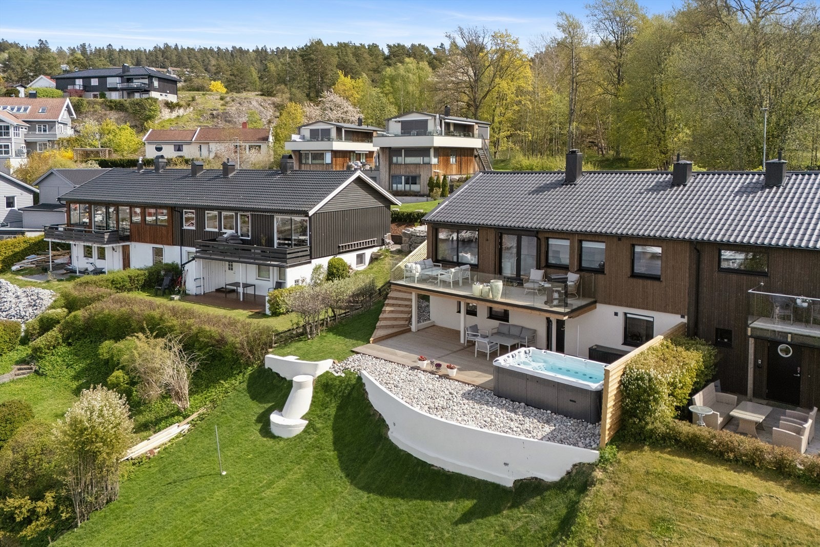 Tomten er pent opparbeidet med støttemurer, plen og beplantning. Galleribilde
