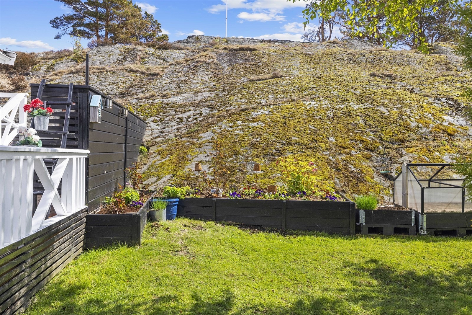 Tomten er opparbeidet med plen, plantekasser og svaberg som glir over i naturen. Galleribilde