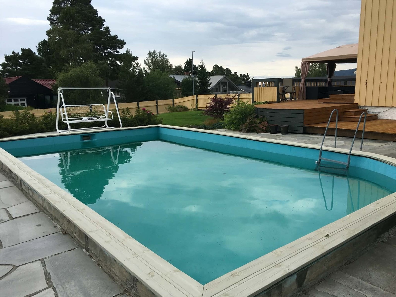 Svømmebassenget i hagen med terrasse og paviljong i bakgrunn. (Bilde tatt av eier) Galleribilde