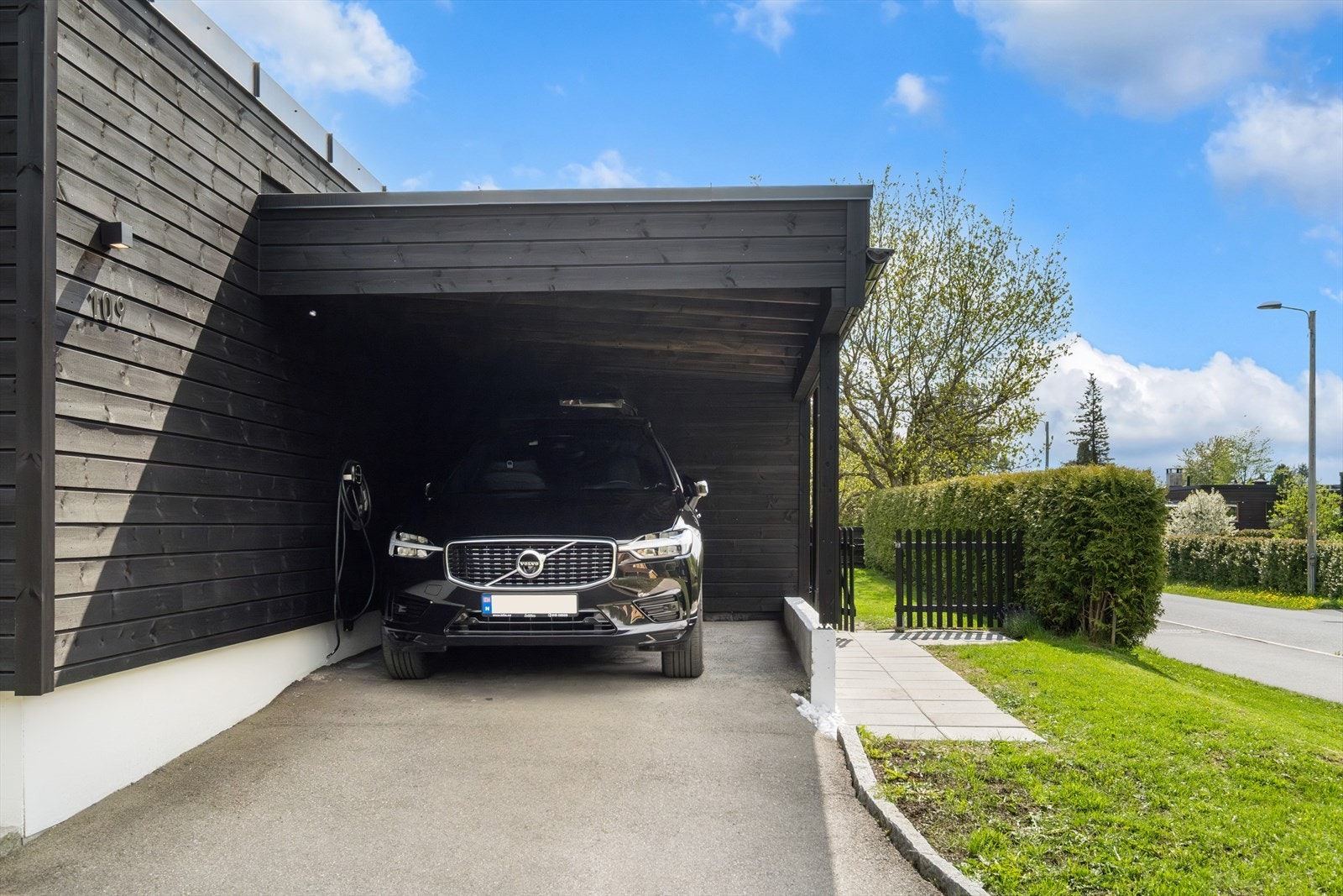 Ved siden av boligen er det en er romslig carport med asfaltert dekke og El-billader Galleribilde