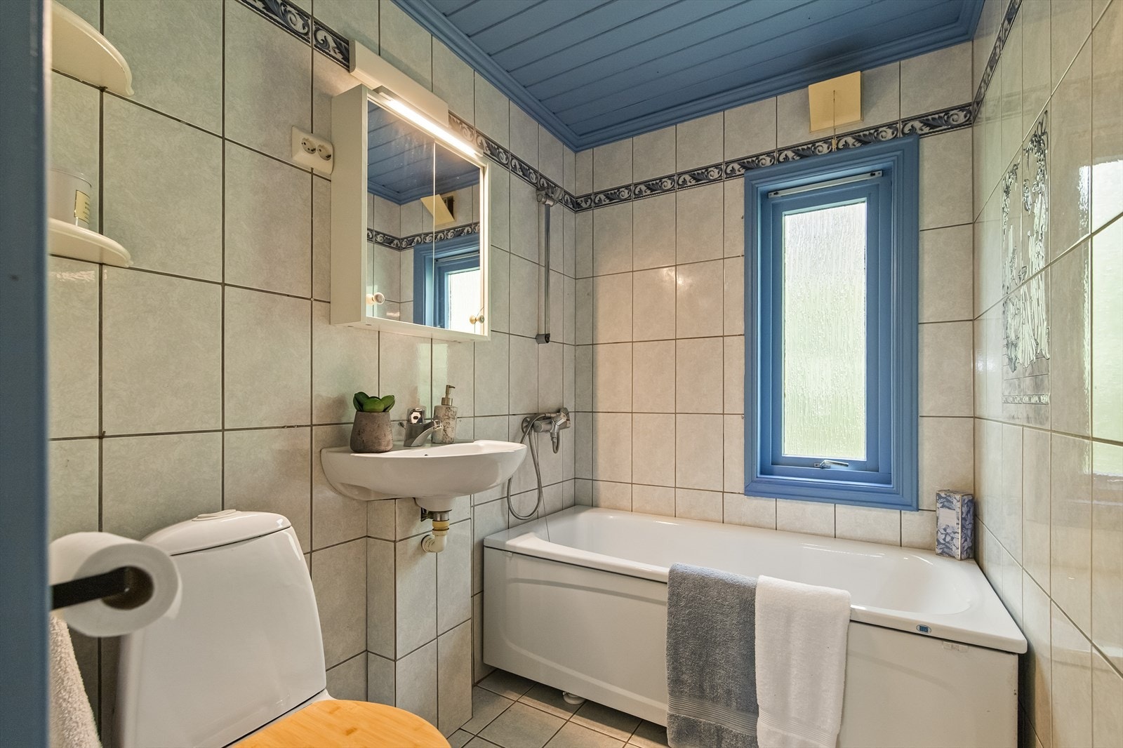 Badet er flislagt og har badekar. Gulvvarmen er i ustand. Galleribilde