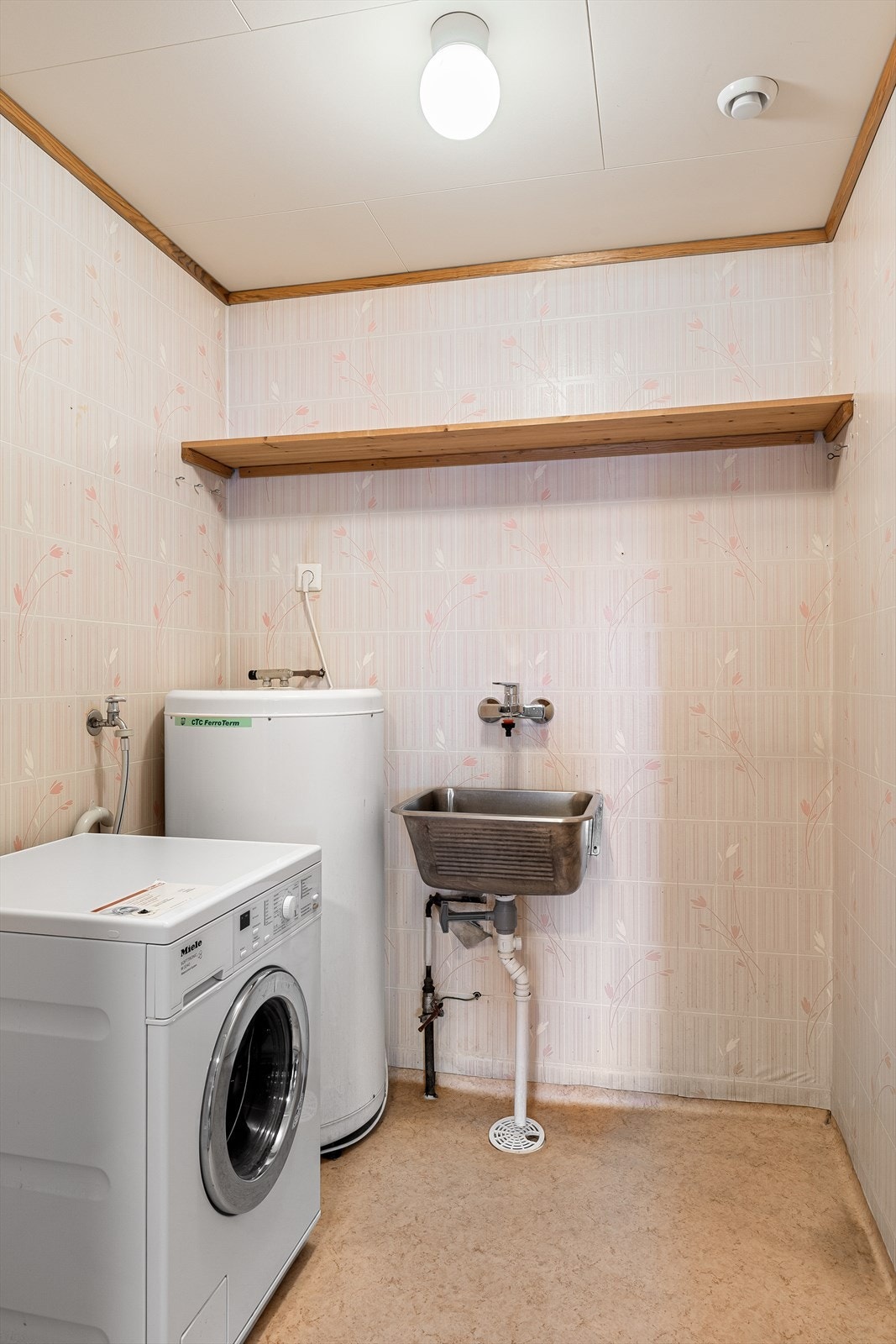 Praktisk, separat vaskerom med vinylbelegg på gulv, utslagsvask og opplegg for vaskemaskin. Galleribilde