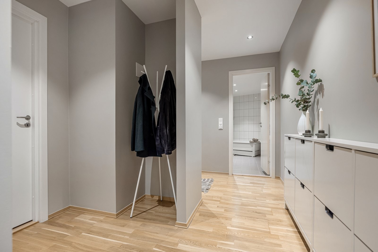Lys gang med parkettgulv og plassbygde løsninger. Galleribilde