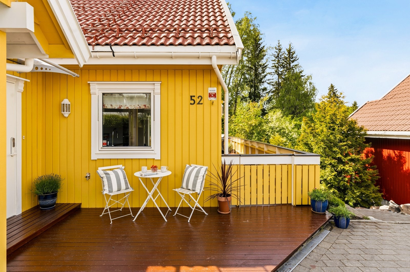 Koselig terrasse ved inngangspartiet med plass til sittegruppe og blomster. En lun plass for morgenkaffe eller en liten pause i solen. Galleribilde