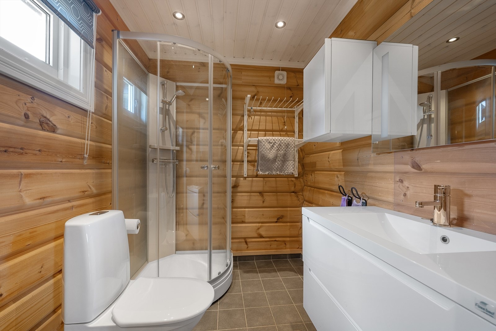 Badet har flislagt gulv med gulvvarme, dusjkabinett og baderomsinnredning med servant. Galleribilde