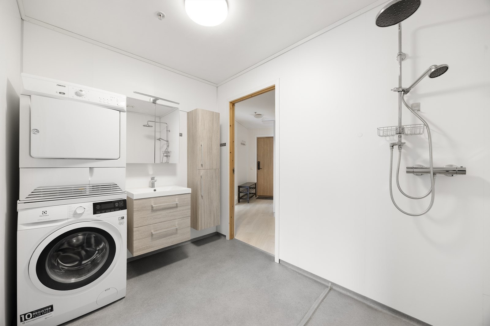 Badet har vinylbelegg på gulv med varmekabler. Rommet er innredet med toalett, opplegg for vaskemaskin og servantinnredning. Galleribilde