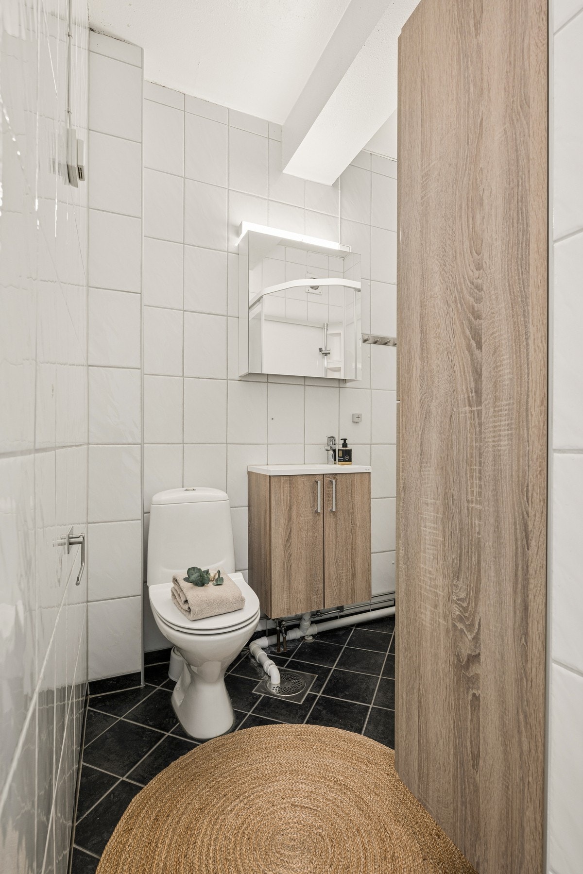 Badet er flislagt og har oppbevaringsplass med servantskap, speilskap og høyskap, samt dusjkabinett og toalett. Galleribilde