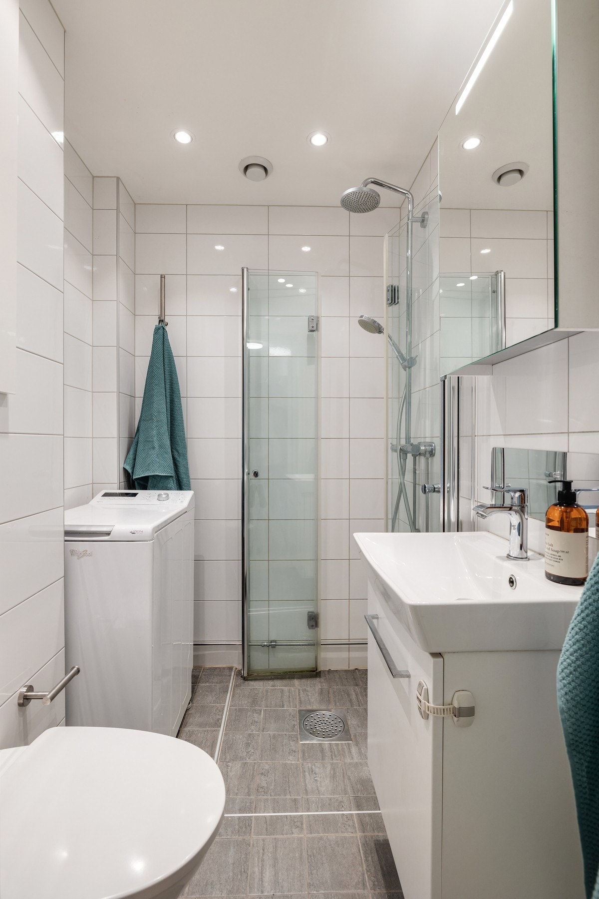 Badet har vegghengt toalett med innebygd sisterne kasse og servant på
vegghengt servantskap. Galleribilde