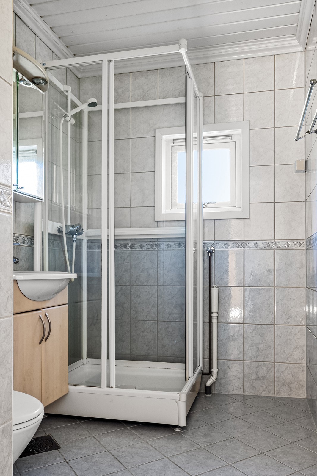 Flislagt bad med elektriske varmekabler i gulvet, dusjkabinett og opplegg for vaskemaskin. Galleribilde