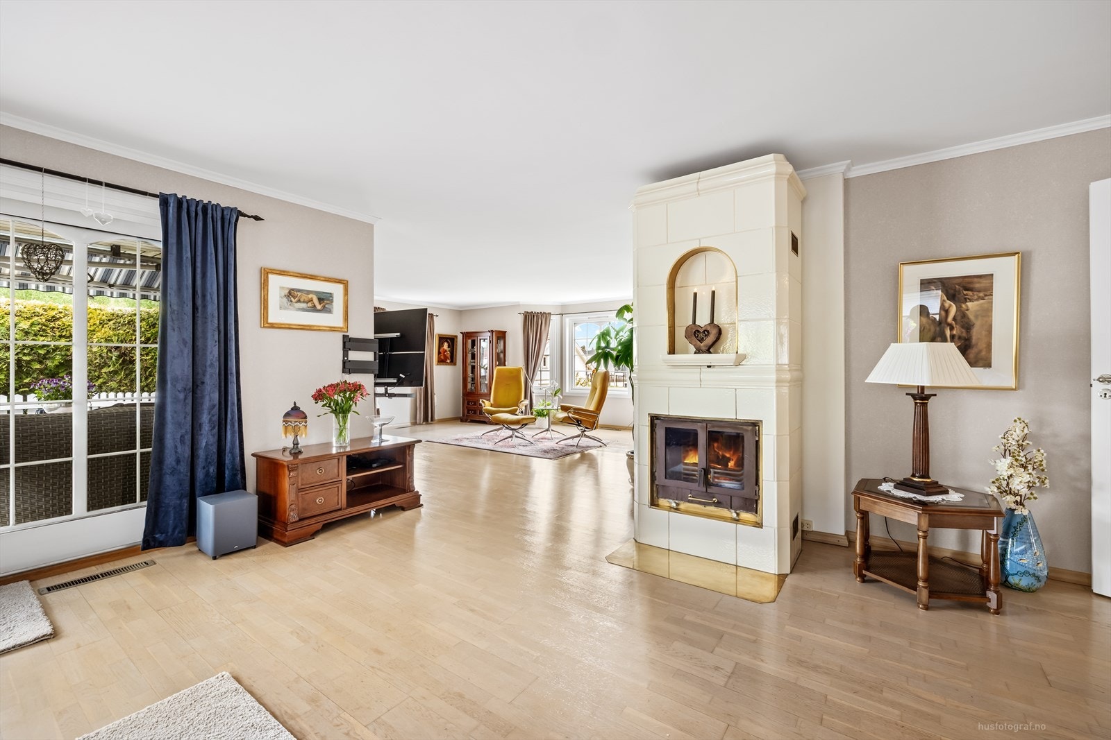 Stuen er et lyst og åpent rom, med en elegant kakkelovn som et sentralt element. Galleribilde