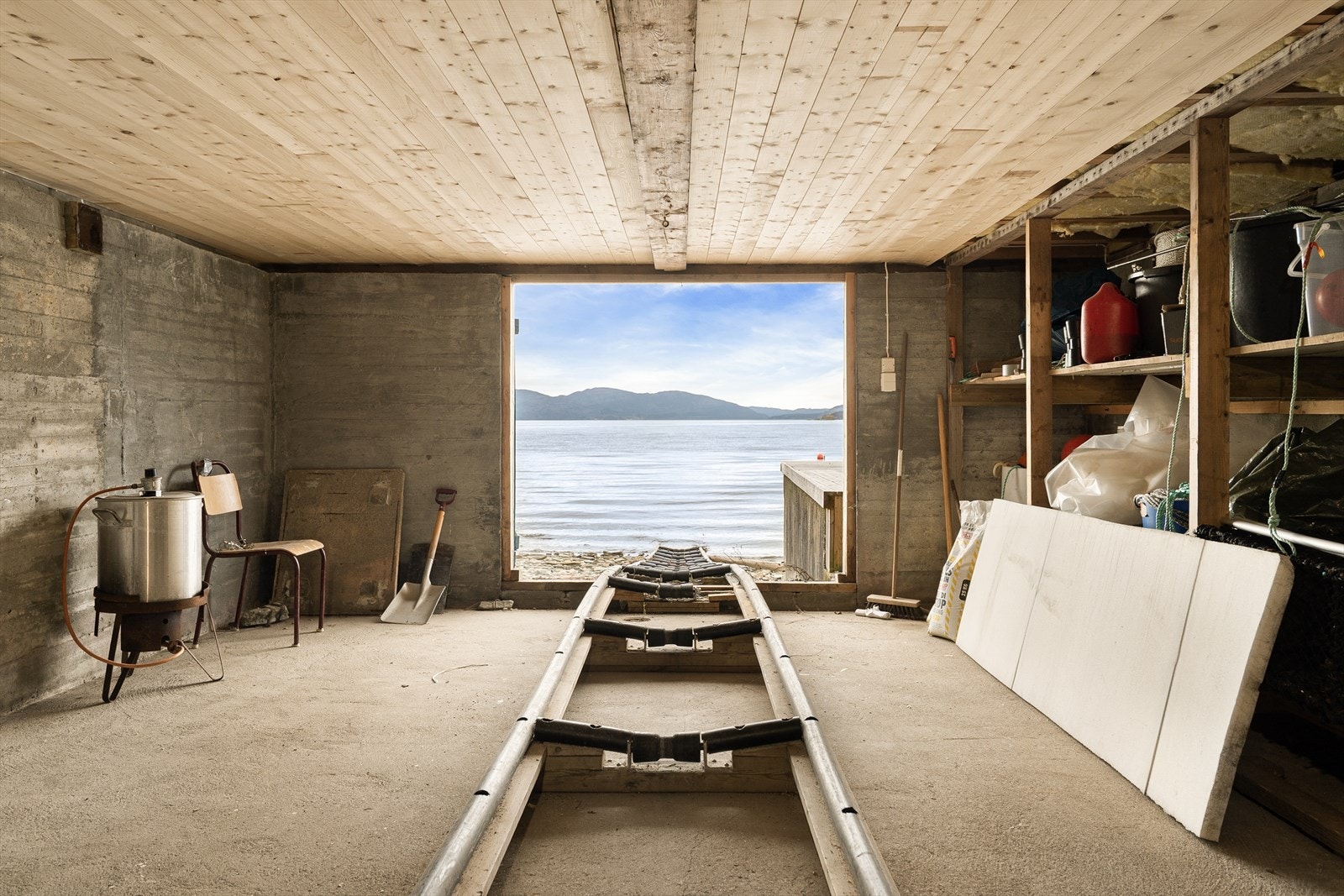 1. etasje i naustet er oppmålt til ca. 30 m², men er ikke måleverdig som bruksareal grunnet lav takhøyde. Det er her etablert skinnegang/båtslipp ut mot sjøen, som gir en praktisk løsning for opptrekk og utsetting av mindre båt. Galleribilde