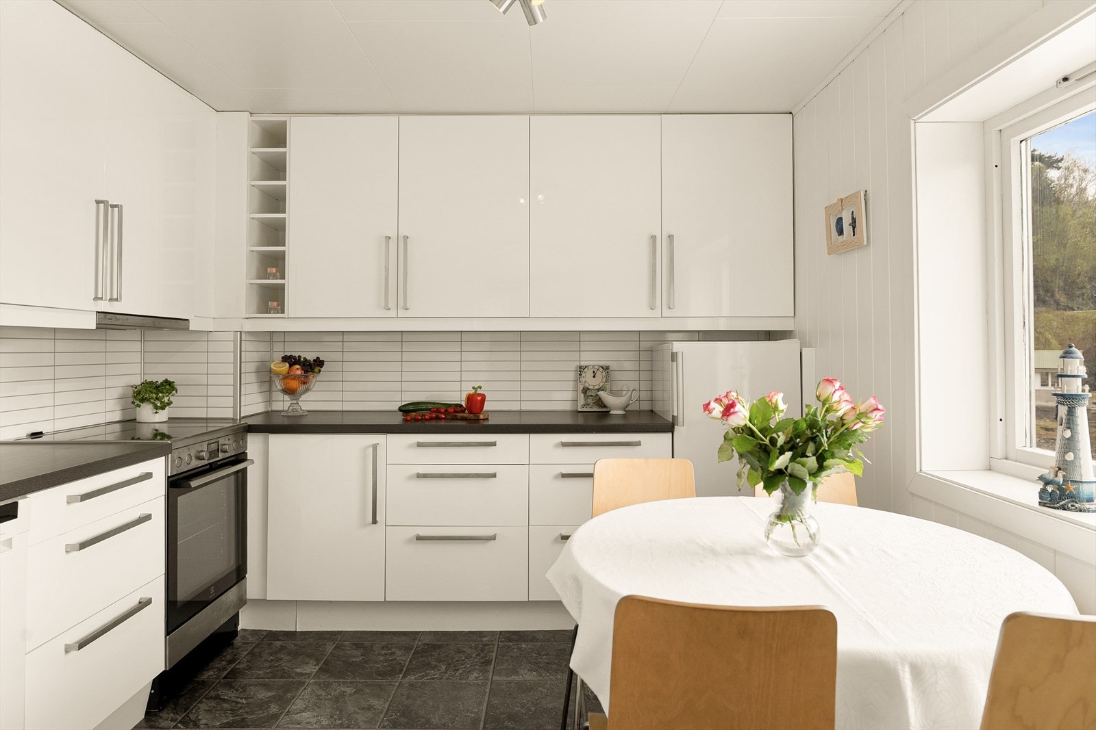 Kjøkkenet fremstår lyst og funksjonelt med glatte fronter, laminert benkeplate, nedfelt kjøkkenvask, benkeskapsbelysning og ventilator i overskap. Galleribilde
