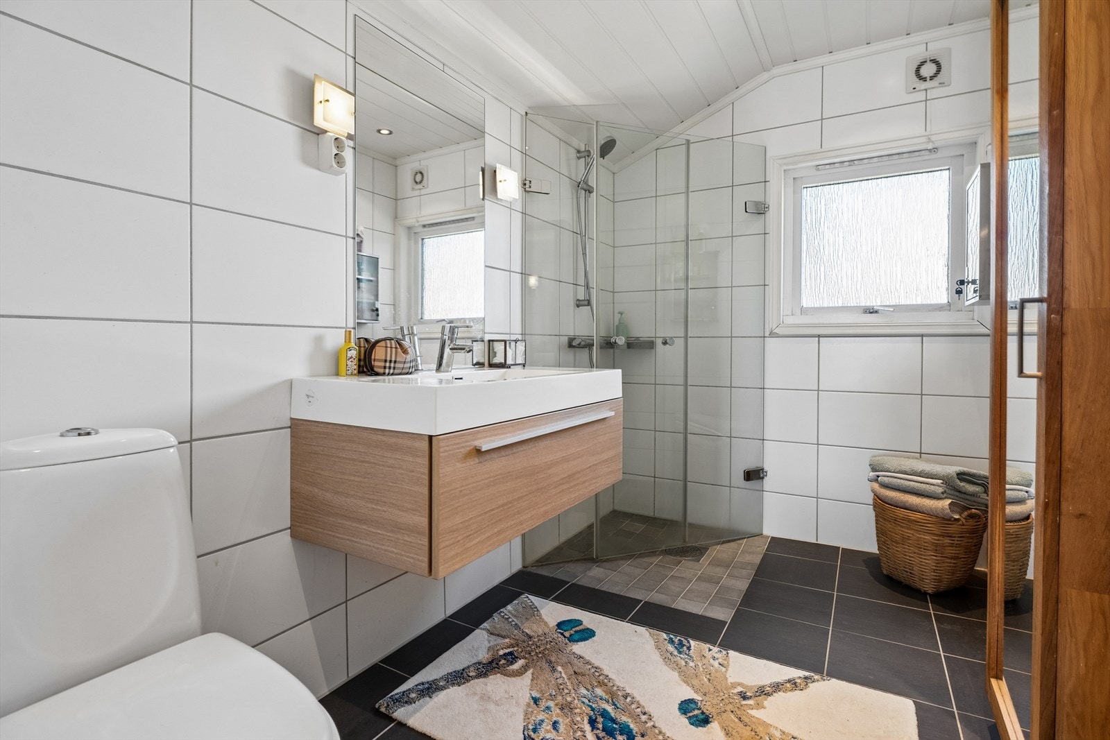 Badet på mellomplanet er flislagt og har varme i gulvet, downlights i taket og dusjhjørne med glassdører. Galleribilde