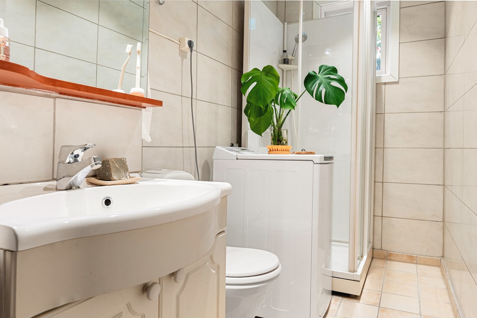 Badet har en praktisk innredning med dusjkabinett, servant med oppbevaring, toalett og opplegg for vaskemaskin. Galleribilde
