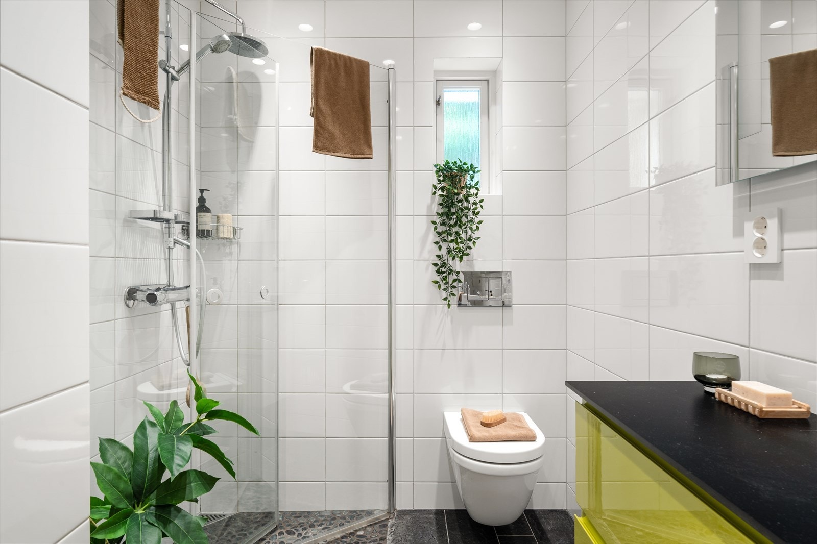 Badet er utstyrt med innfelbart dusjhjørne i glass, vegghengt toalett, møblement med servant og speil. Galleribilde