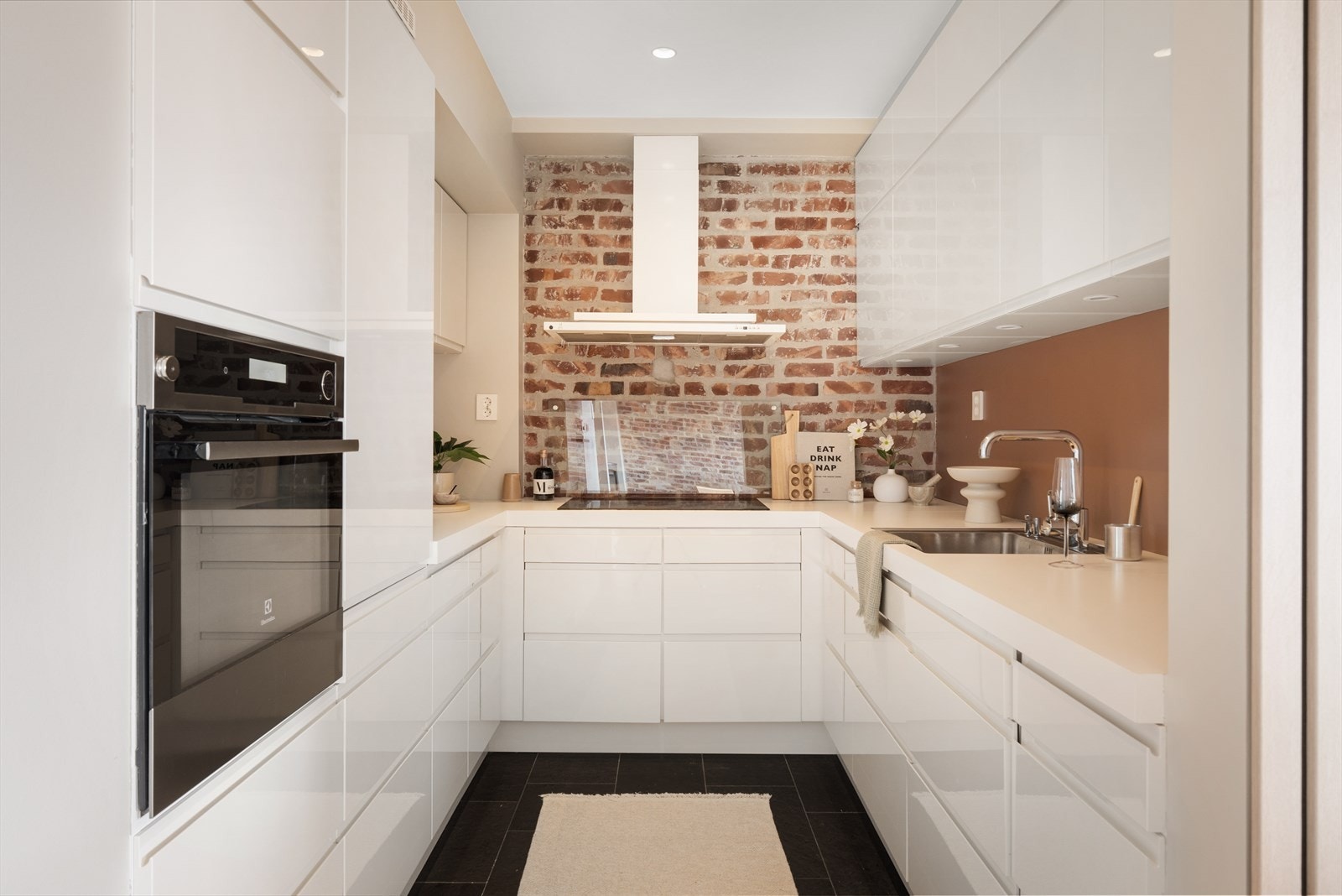 Moderne og lyst kjøkkeninnredning fra Designe, nytt i 2013. Kjøkkeninnredningen har hvit slett høyglans utførelse og takhøye skap. Galleribilde