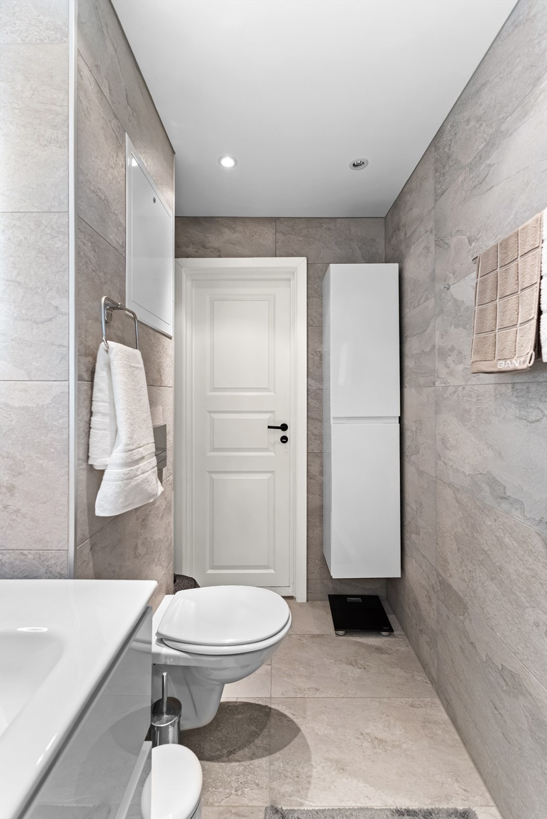 Badet er utstyrt med dusjhjørne med glassvegger, servant med skuffeløsning, vegghengt toalett og opplegg for vaskemaskin. Galleribilde