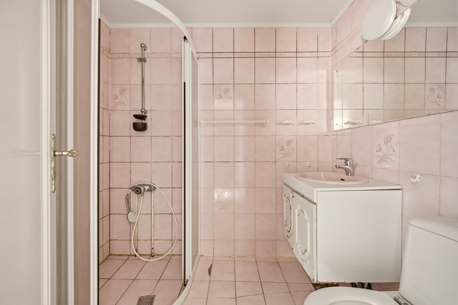 Badet i første etasje har flislagte gulv- og veggflater med servantinnredning, servant, gulvstående toalett og dusjhjørne. Galleribilde