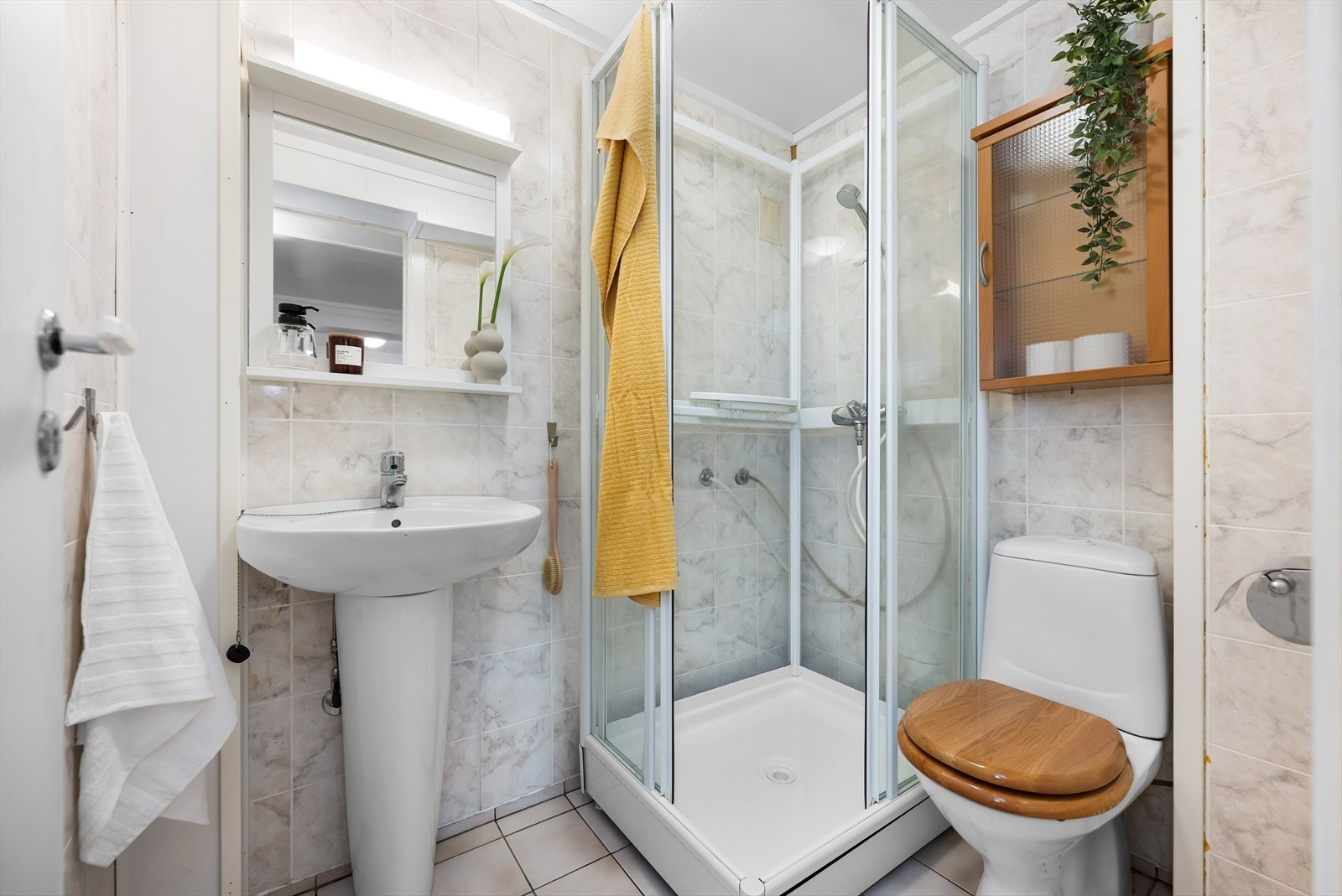 Badet er av noe eldre dato, men godt utnyttet. Her er det blitt plass for både dusjkabinett og søylevask foruten det frittstående toalettet. Galleribilde