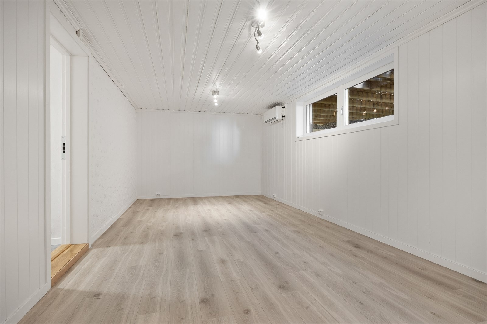 Stort, innredet rom i kjelleren med laminatgulv og varmepumpe for oppvarming. Galleribilde