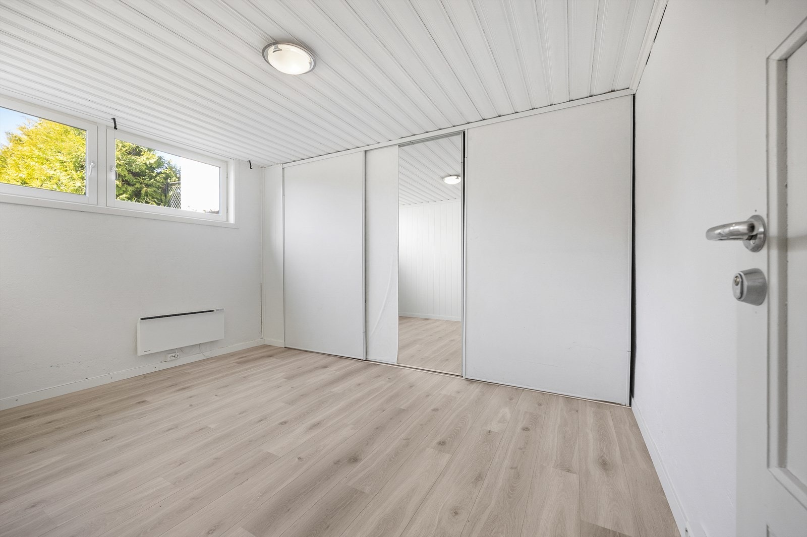 Nok et innredet rom i kjelleren, med garderobeskap og laminat på gulvet. Galleribilde