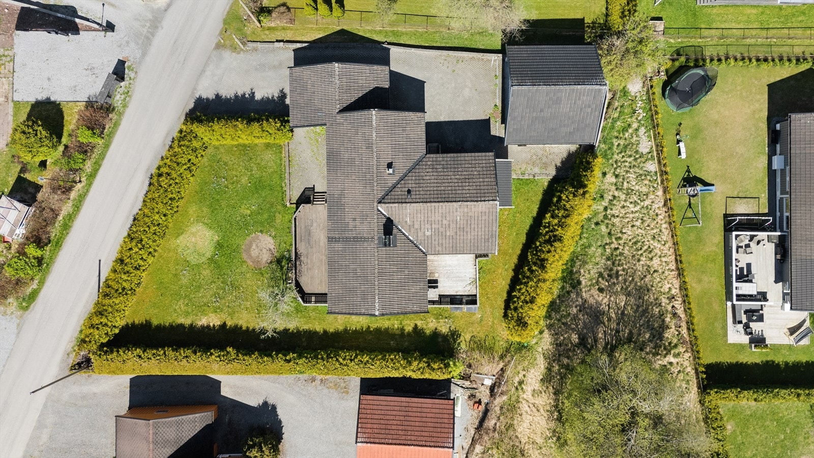 Tomten er avgrenset med hekk mot naboer og vei. Galleribilde