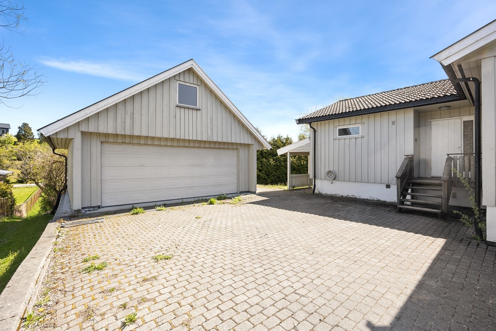 Eiendommen har en stor, steinbelagt gårdsplass og en frittstående dobbelgarasje fra 2007 med loft. Galleribilde