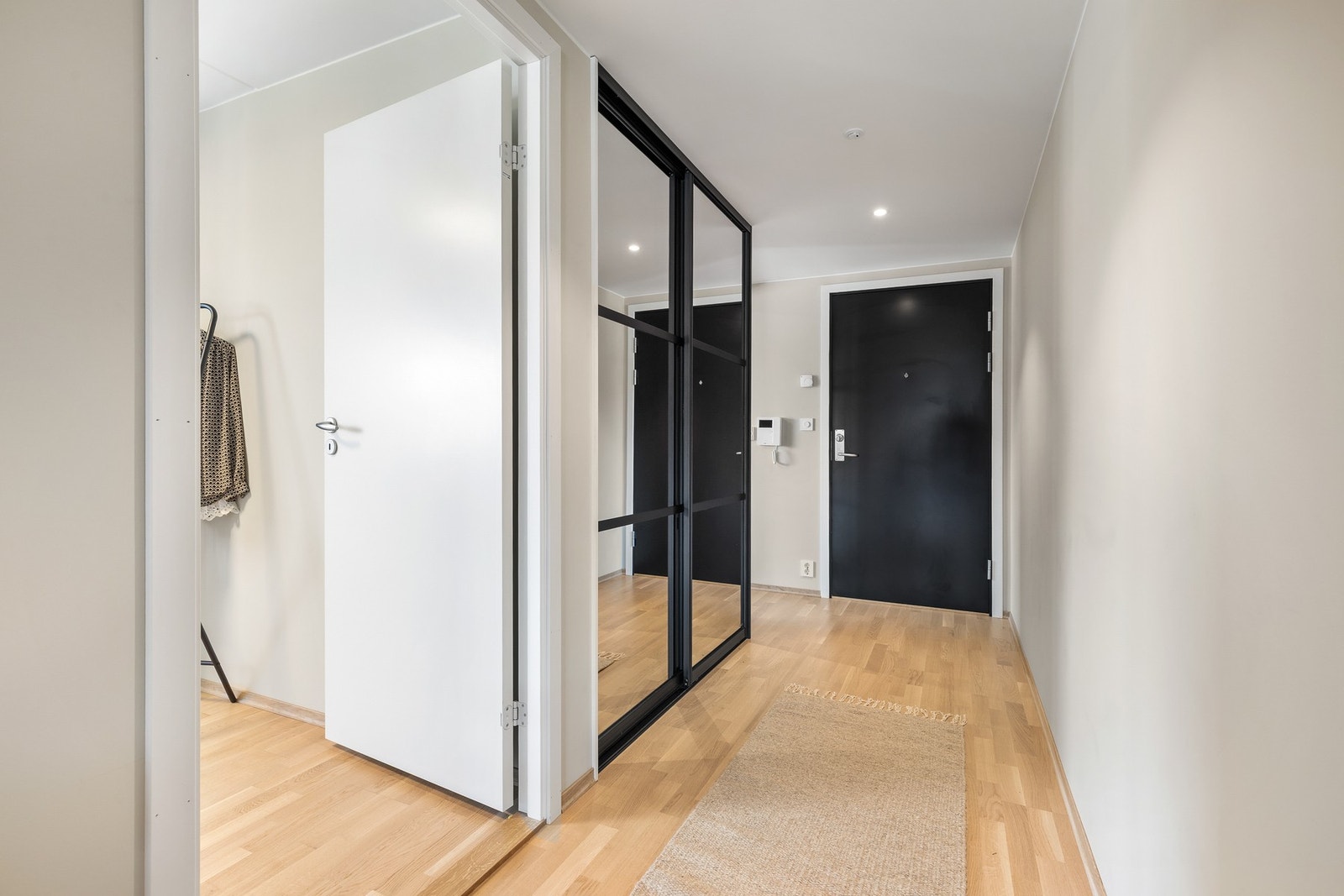 Det er montert skyvedørsgarderobe med speilfronter for oppbevaring av yttertøy og sko Galleribilde