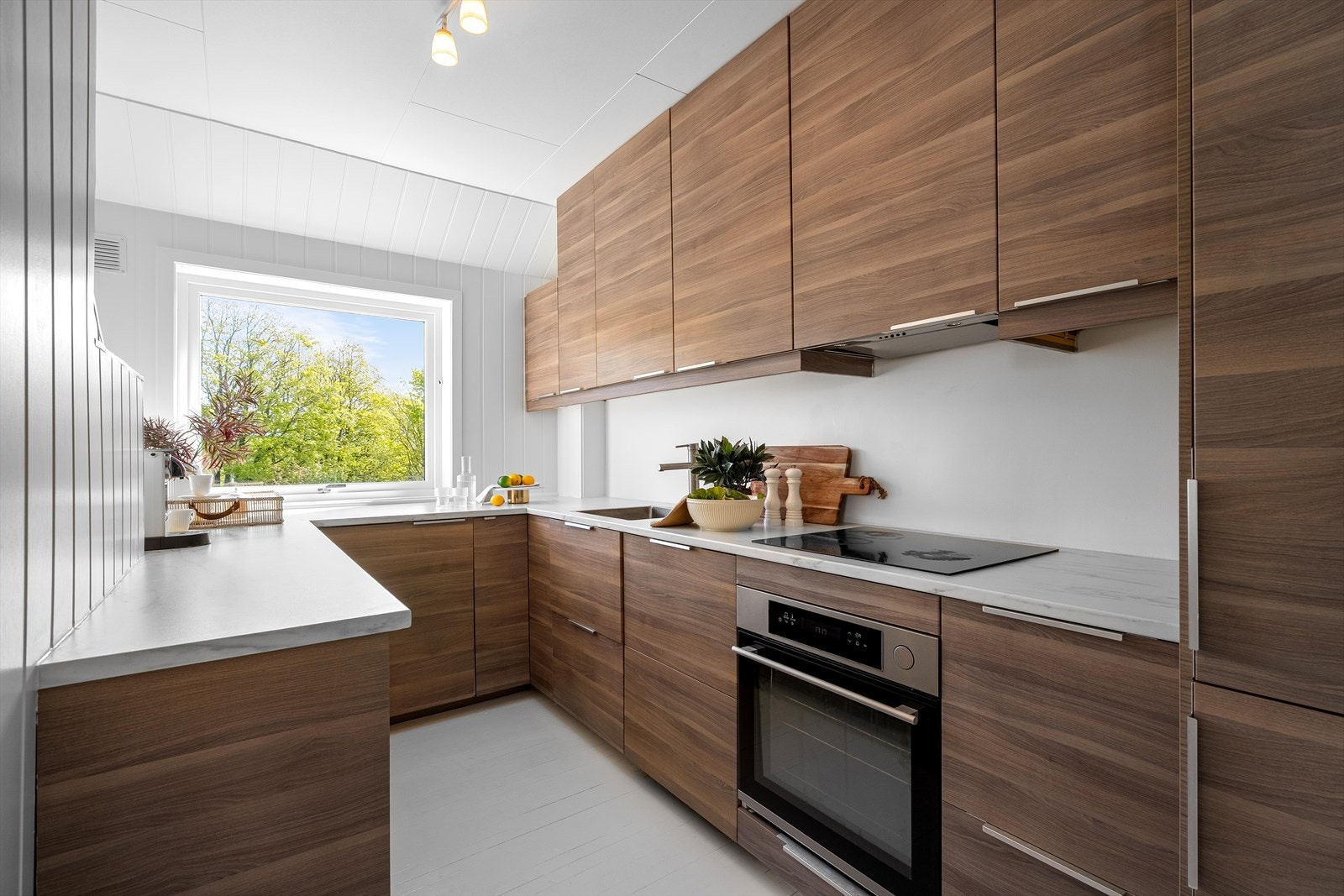 Moderne IKEA-kjøkken fra 2016 med slette fronter, tregulv og panelvegger som skaper en hyggelig atmosfære. Galleribilde