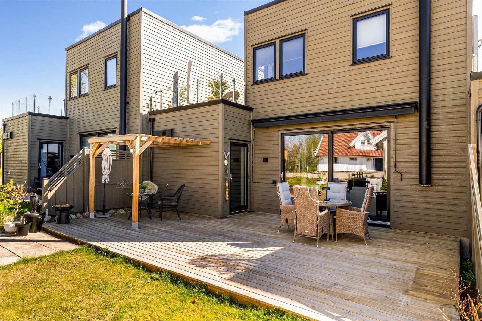 Terrassen gir god plass til spisebord og sittegruppe. En pergola er satt opp på terrassen. Galleribilde